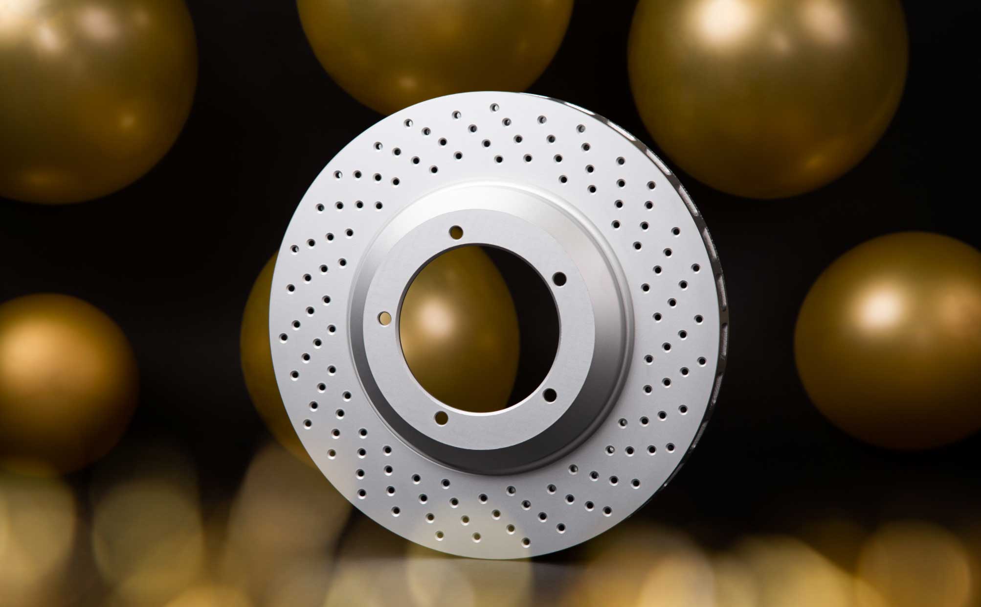 A single drilled rotor, lit against a dark background - The Best Brakes and Rotors for Highway Driving