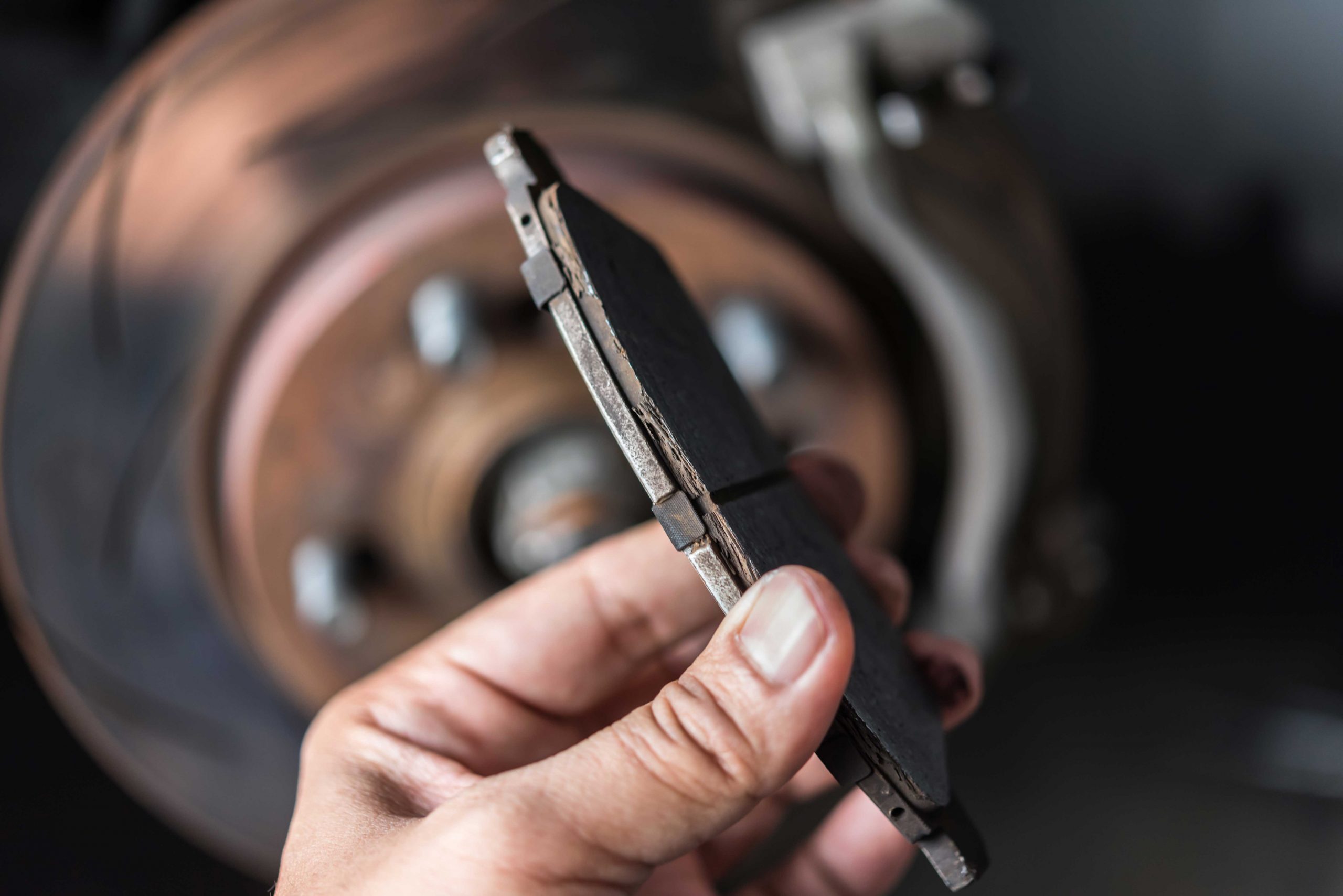 A worn pad held against a heavily rusted rotor - 5 Signs You Need New Brake Pads: Don’t Ignore These Warnings